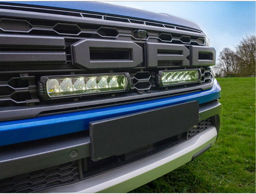 Close-up of a Ford truck grille with LED lights on a grassy background