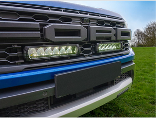 Close-up of a Ford truck grille with LED lights on a grassy background
