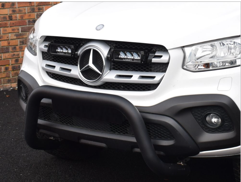 Front view of a white Mercedes-Benz vehicle with a black grille guard on a dark surface with Lazer Lamps Mercedes X-Class (2017+) Grille Kit