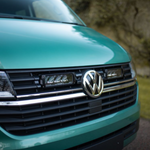 Close-up of a teal Volkswagen van with a blurred natural background and Lazer Lamps Grille Kit for VW Transporter T6.1