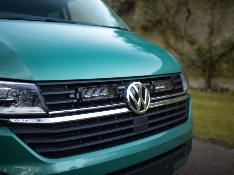 Close-up of a teal Volkswagen van with a blurred natural background and Lazer Lamps Grille Kit for VW Transporter T6.1
