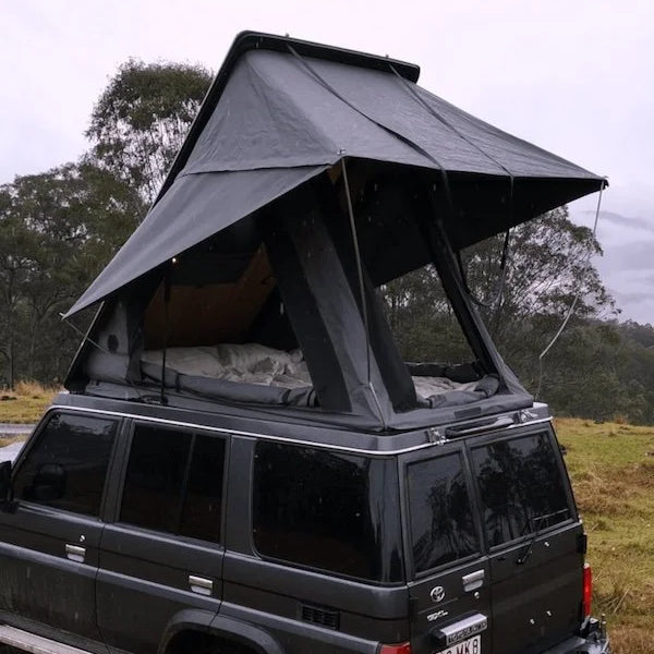 Black SUV with a rooftop tent in a natural setting