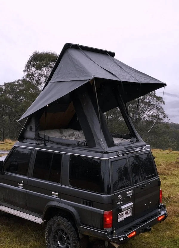 Black SUV with a rooftop tent in a natural setting