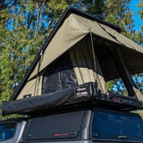 Roof top tent attached to a vehicle with trees in the background