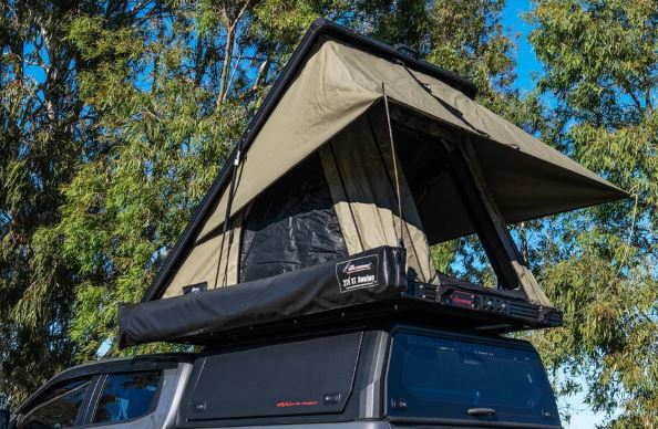Roof top tent attached to a vehicle with trees in the background