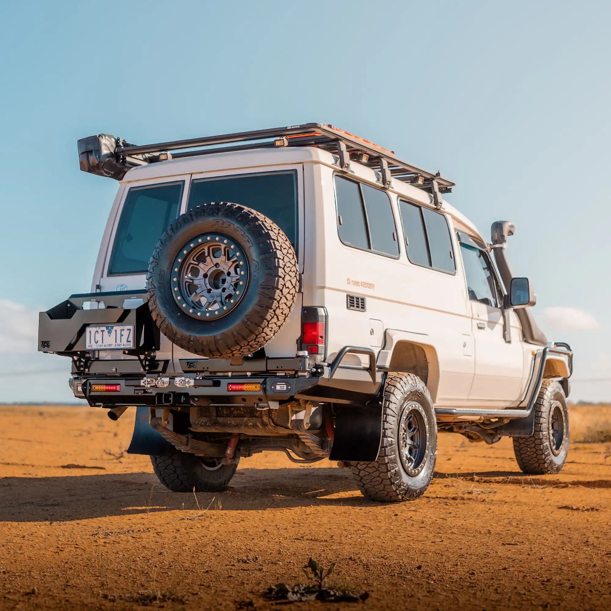 White off-road vehicle with a spare tire on a desert landscape