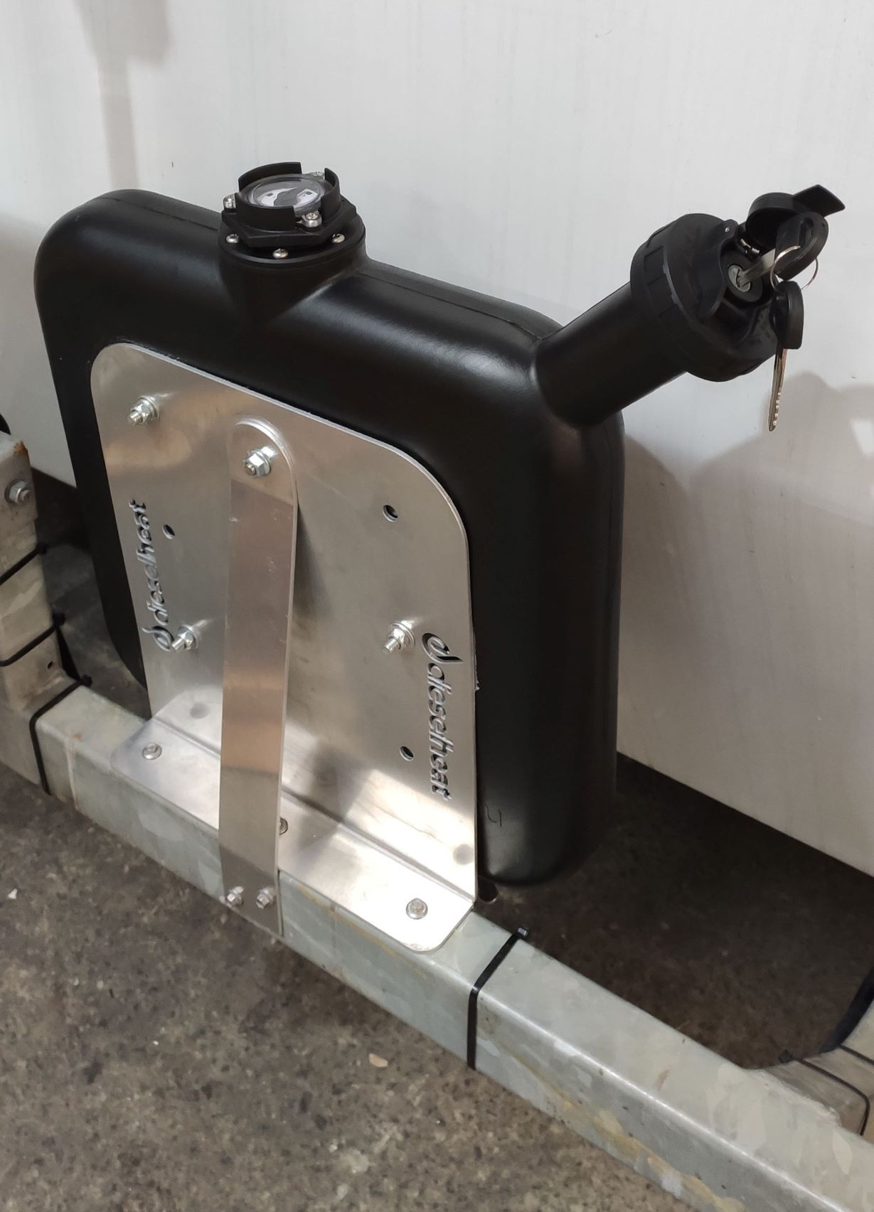Fuel tank with metal bracket attached to a vehicle frame against a white background