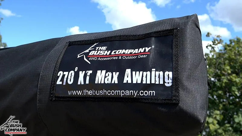 Black awning with 'The Bush Company' branding against a blue sky and green trees.