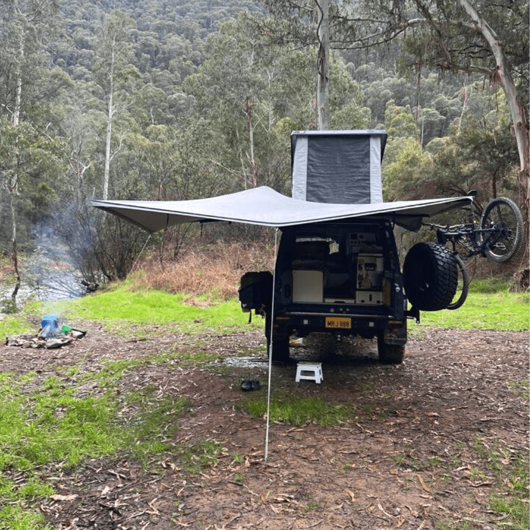 Camper van with an extended awning in a forest setting