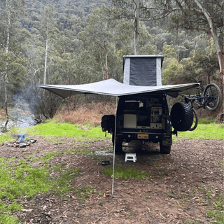 Camper van with an extended awning in a forest setting