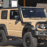 Beige off-road vehicle with black roof rack and bumper in a showroom setting
