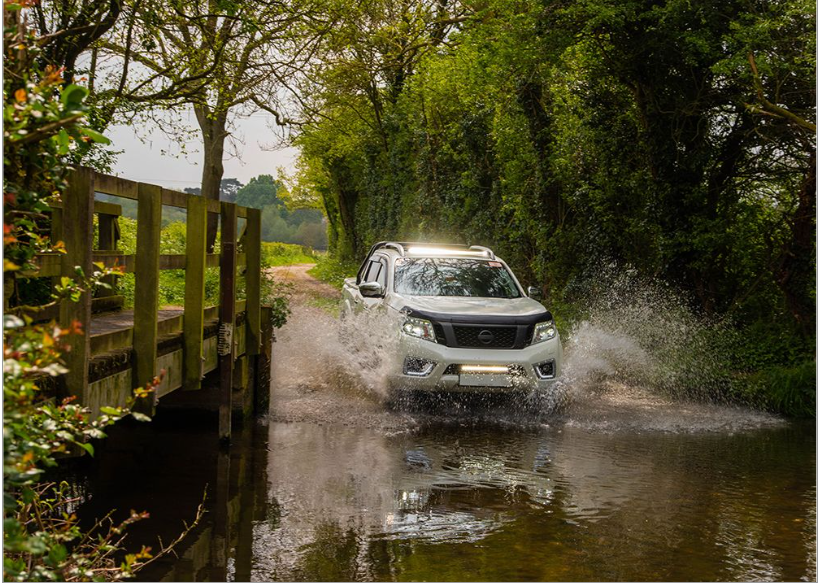 White SUV driving through a shallow stream on a forest road