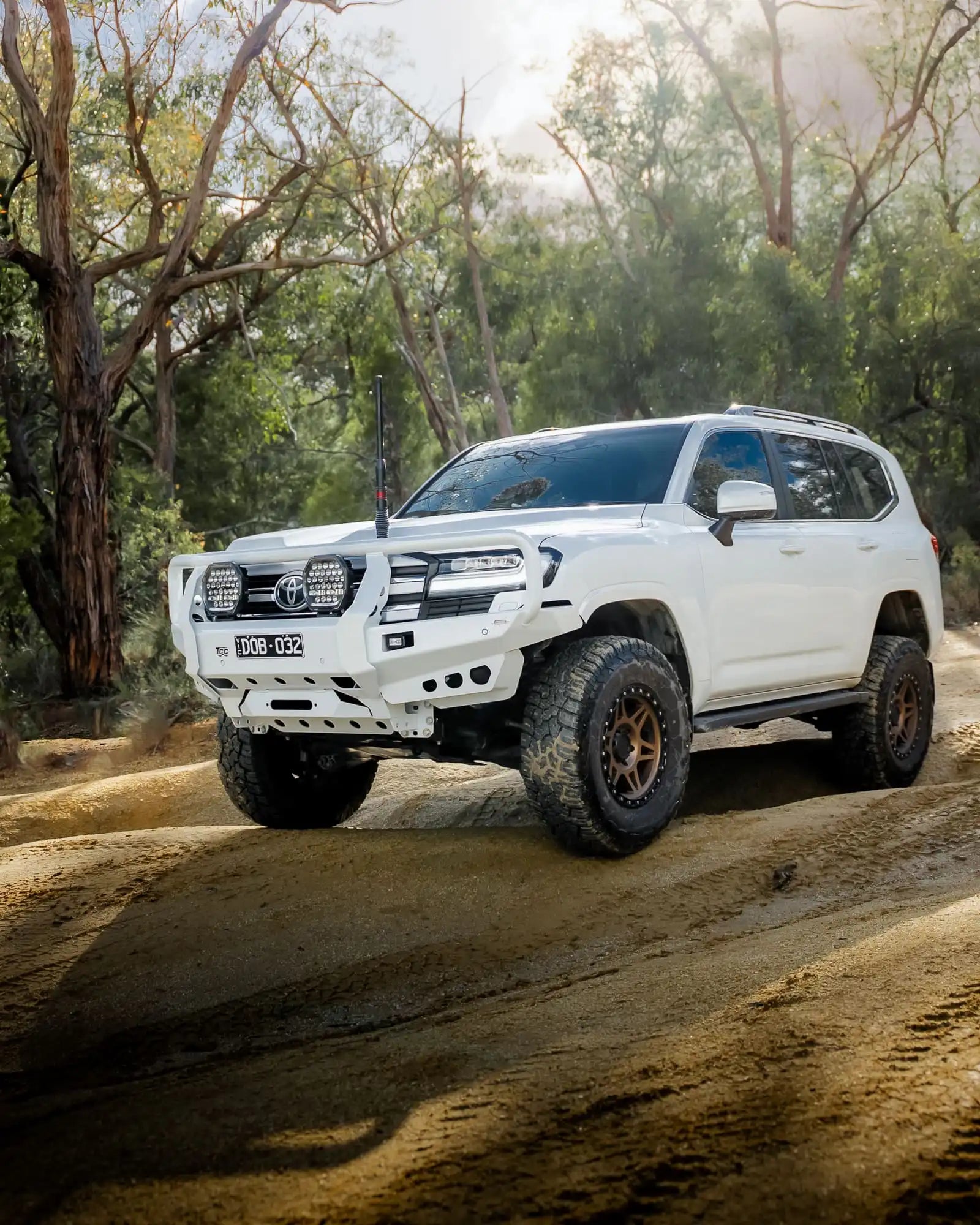 White Toyota SUV driving on a dirt road in a forested area