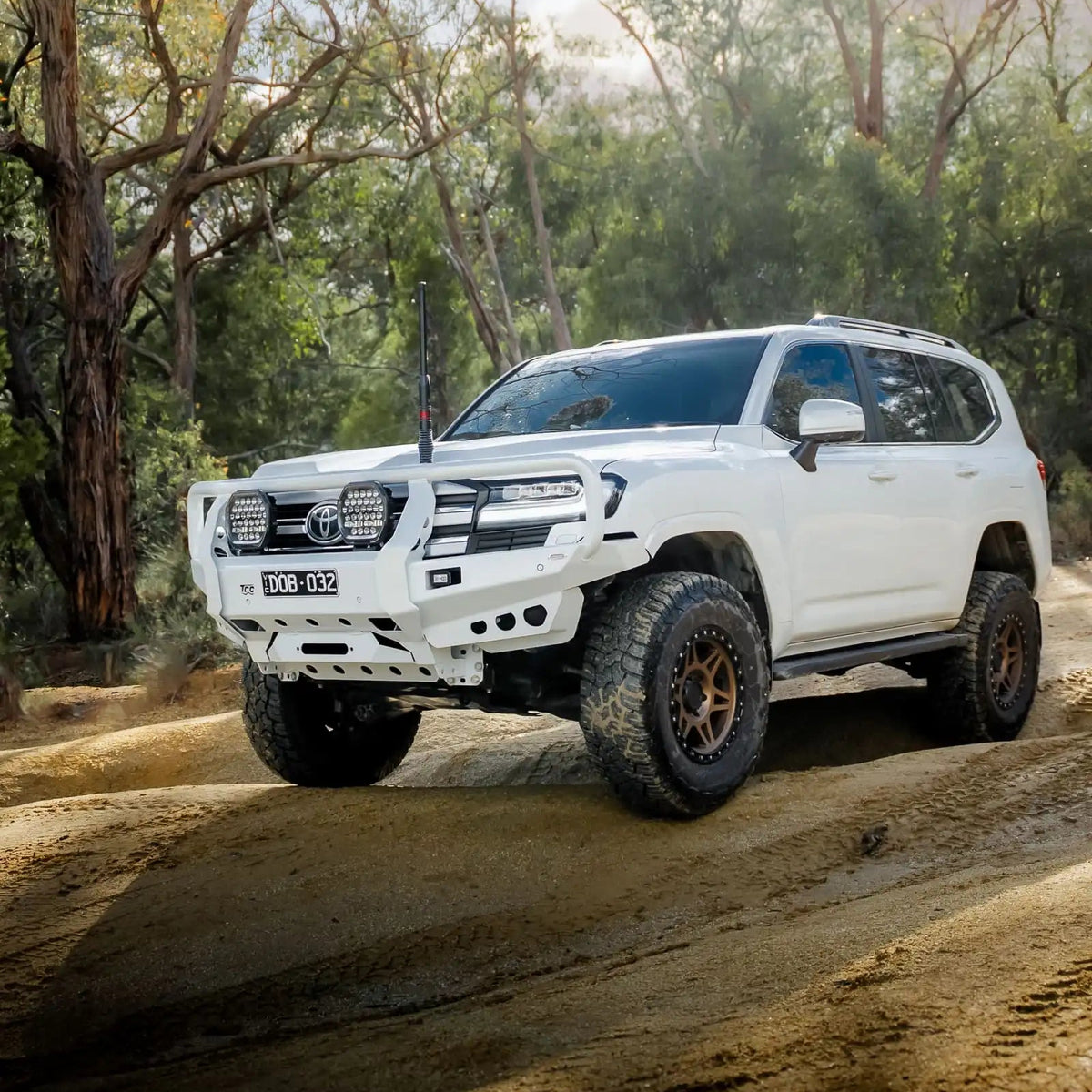 White Toyota SUV driving on a dirt road in a forested area