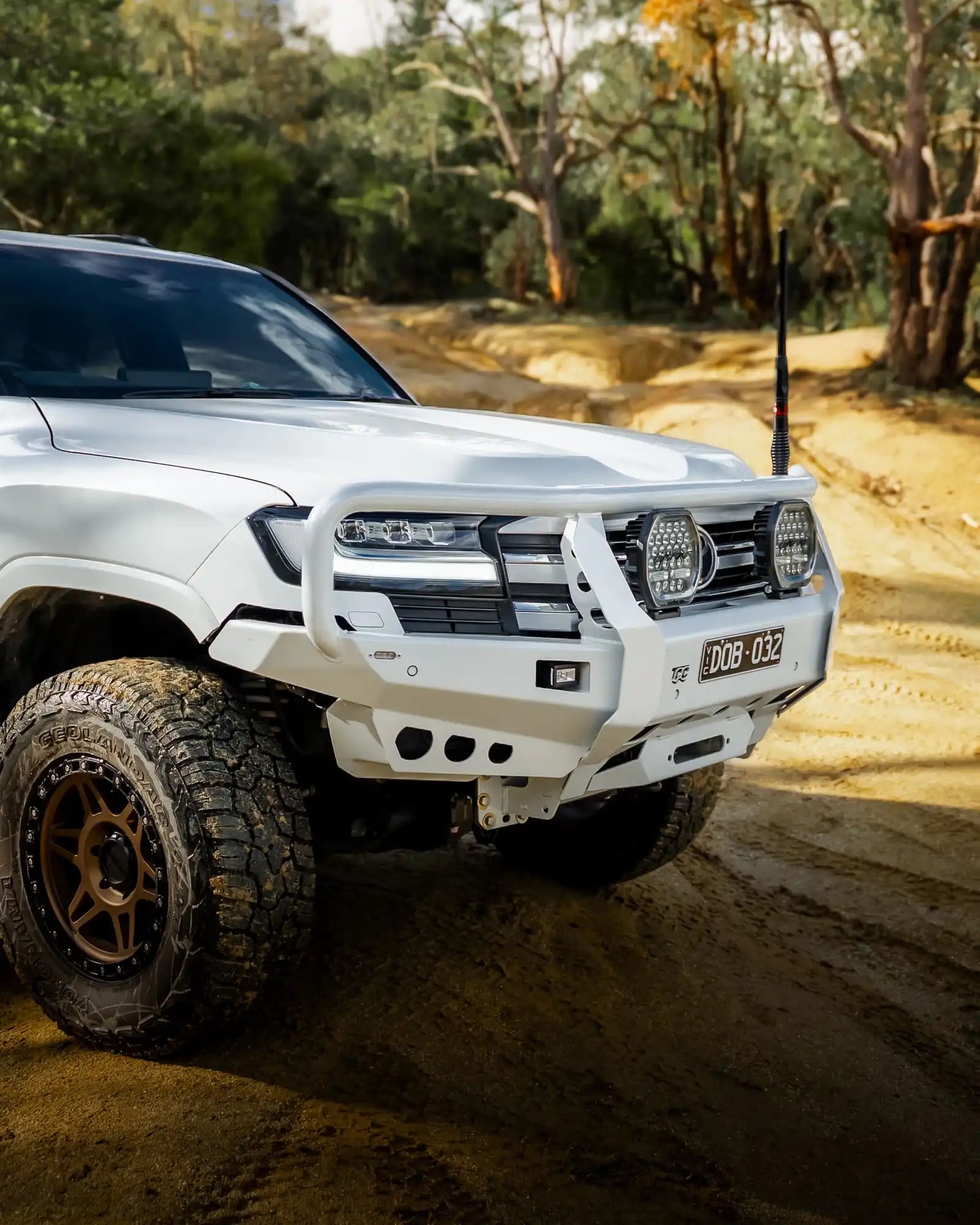 White off-road vehicle on a dirt road with trees in the background