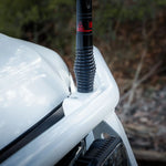 Car antenna on a white vehicle with a blurred natural background