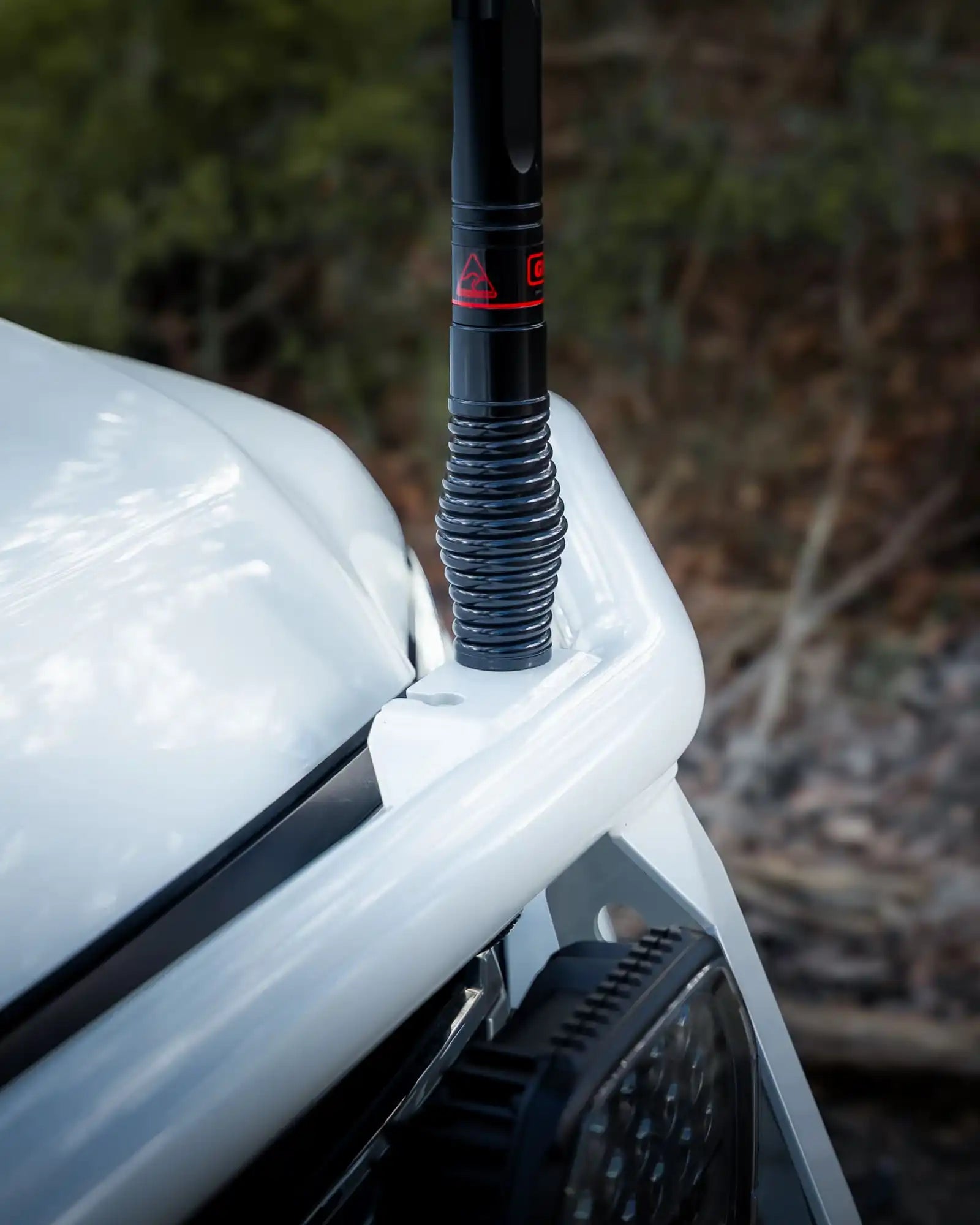Car antenna on a white vehicle with a blurred natural background