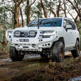 White Toyota SUV driving through a forest on a muddy path