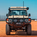 Front view of a rugged off-road vehicle on a dirt road with clear blue sky.