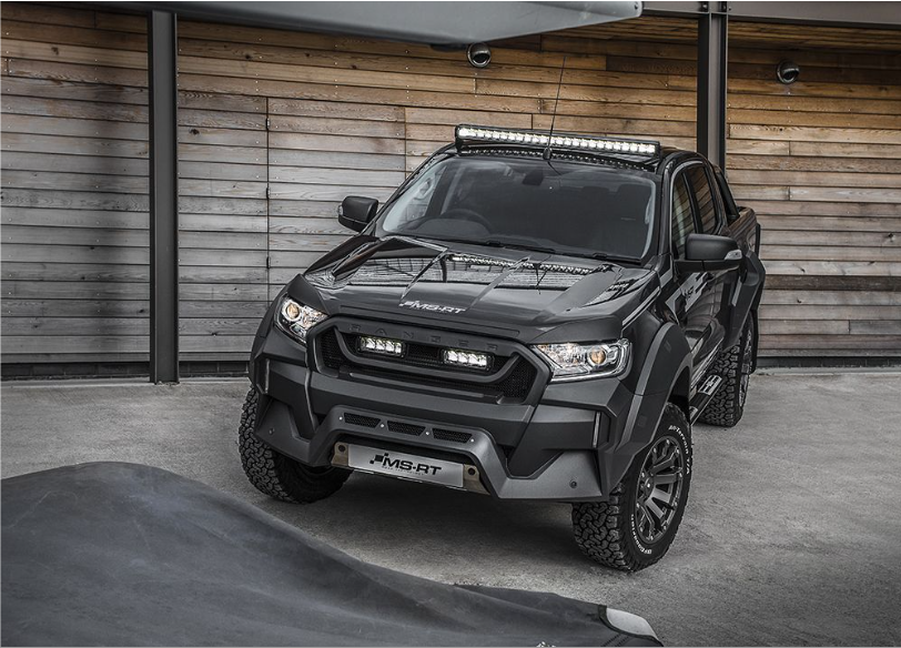 Black off-road vehicle with additional Lazer Lamps Roof Mount Kit – Ford Ranger (2016+ No Roof Rails) lights in front of a wooden wall.