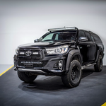 Black Toyota pickup truck with additional lights on a gray background