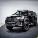 Black Toyota pickup truck with additional lights on a gray background