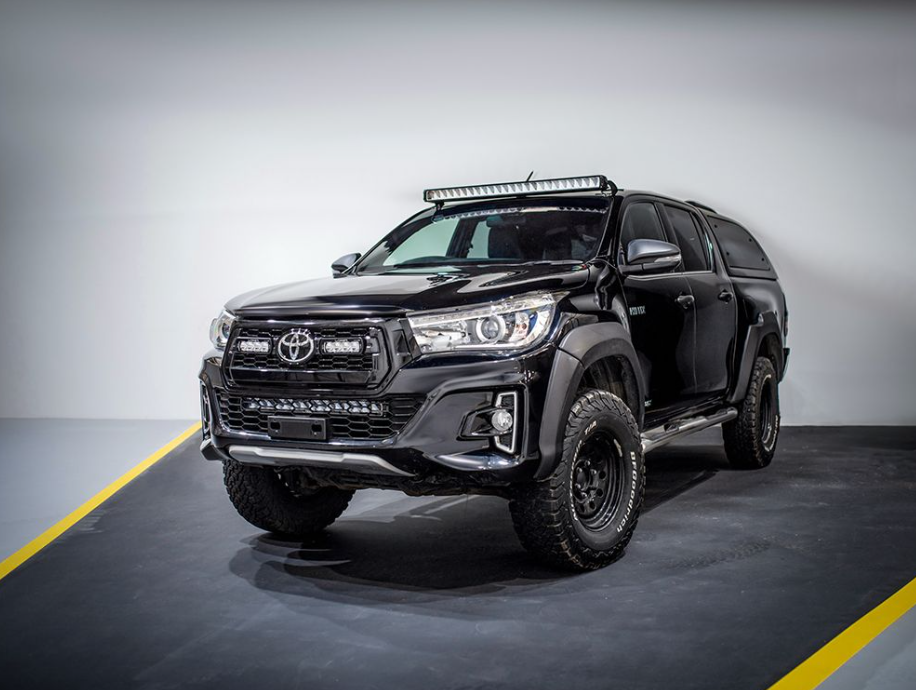 Black Toyota pickup truck with additional lights on a gray background