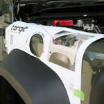 Car fender with a repair kit labeled 'torqit' on a car with an open hood.