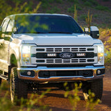 White Ford truck on a dirt road with desert landscape and Lazer Lamps Grille Kit – Ford F-250 & F-350 XL/XLT (2023+)