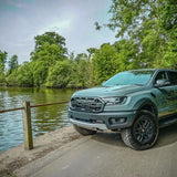Green ford ranger raptor parked by a river with trees in the background with Lazer Lamps Grille Kit – Ford Ranger Raptor (2018–2022)