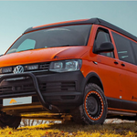 Orange Volkswagen van with off-road modifications on a grassy area with Lazer Lamps Grille Kit for VW Transporter T6 Startline
