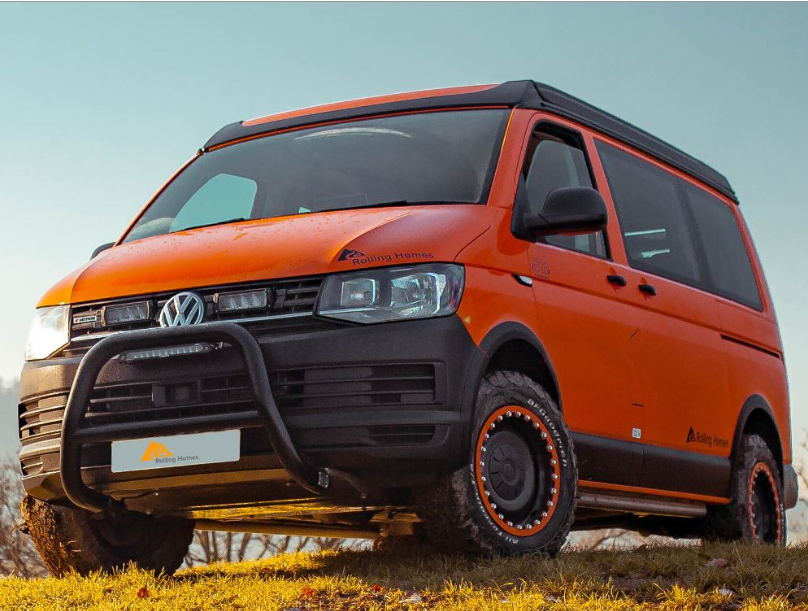 Orange Volkswagen van with off-road modifications on a grassy area with Lazer Lamps Grille Kit for VW Transporter T6 Startline