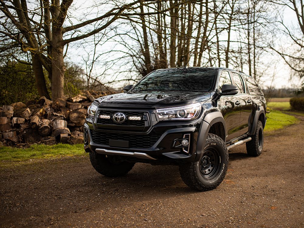 Black Toyota SUV parked on a dirt road with trees in the background