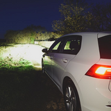 White car parked on a grassy area at night with visible brand logo.