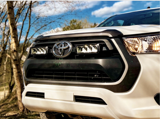 Close-up of a Toyota vehicle's front grille with a blurred natural background