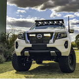White Nissan truck on a grassy area with a cloudy sky