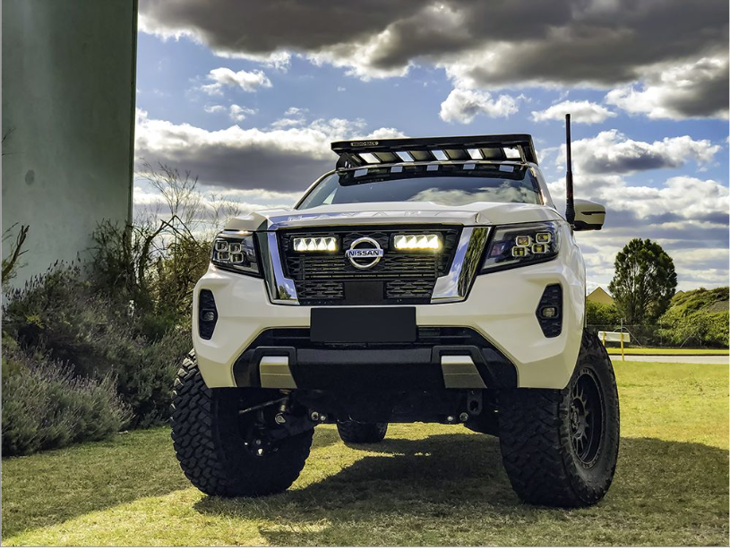 White Nissan truck on a grassy area with a cloudy sky