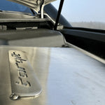 Close-up of a car's hood with a brand logo, showing reflection and texture.