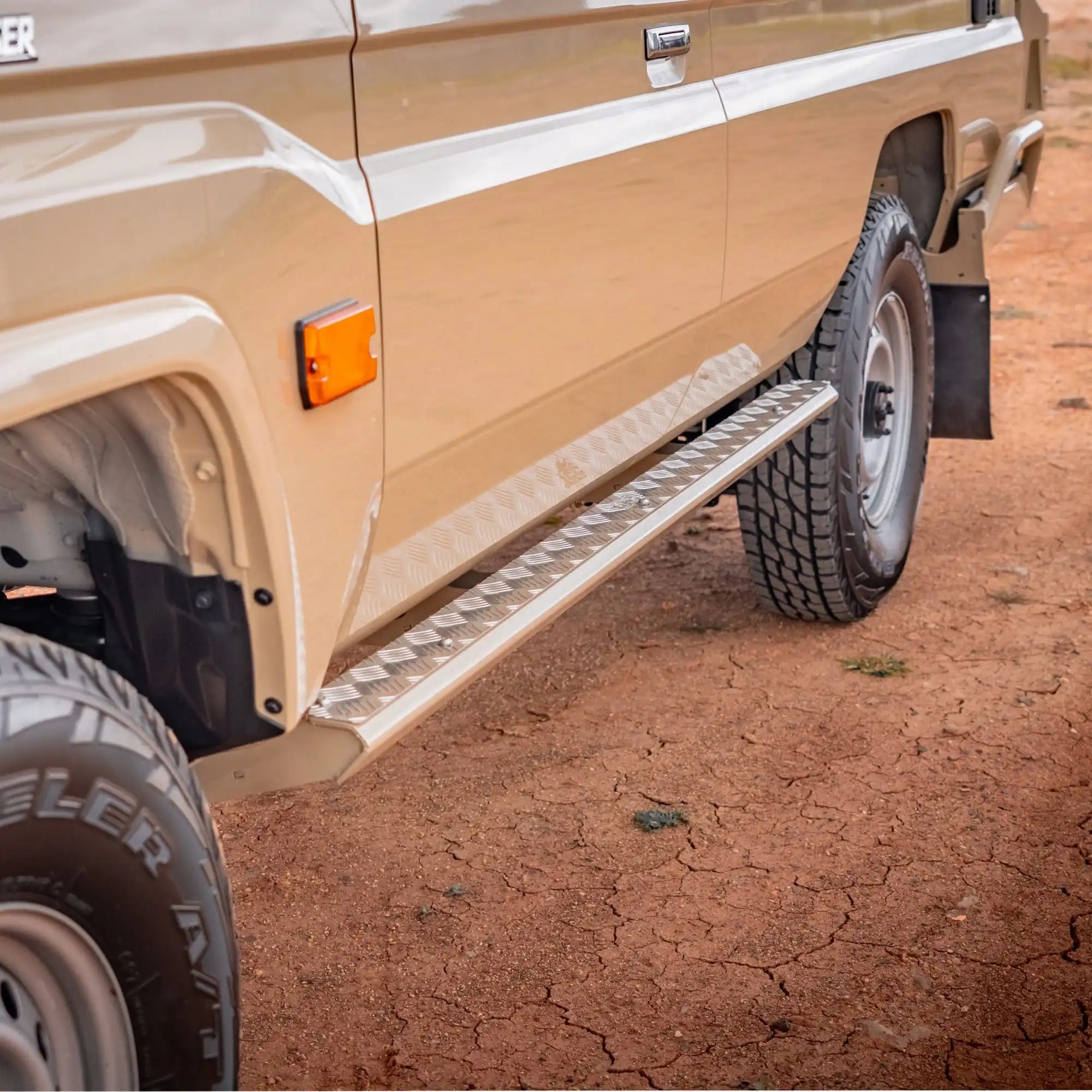 Beige off-road vehicle with a step bar on a dirt surface