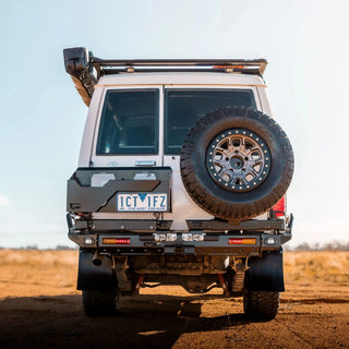 Back view of a rugged vehicle with a spare tire on a dirt road – TCC 78 Series Troop carrier Rear Bar Tow Bar