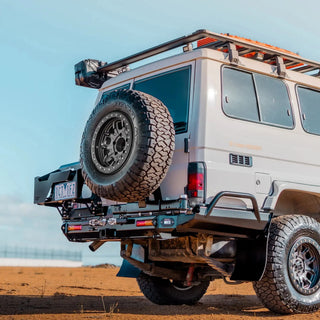 White off-road vehicle with spare tire on a clear day – TCC 78 Series Troop carrier Rear Bar Tow Bar