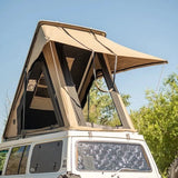 White SUV with a beige rooftop tent set against a clear blue sky.