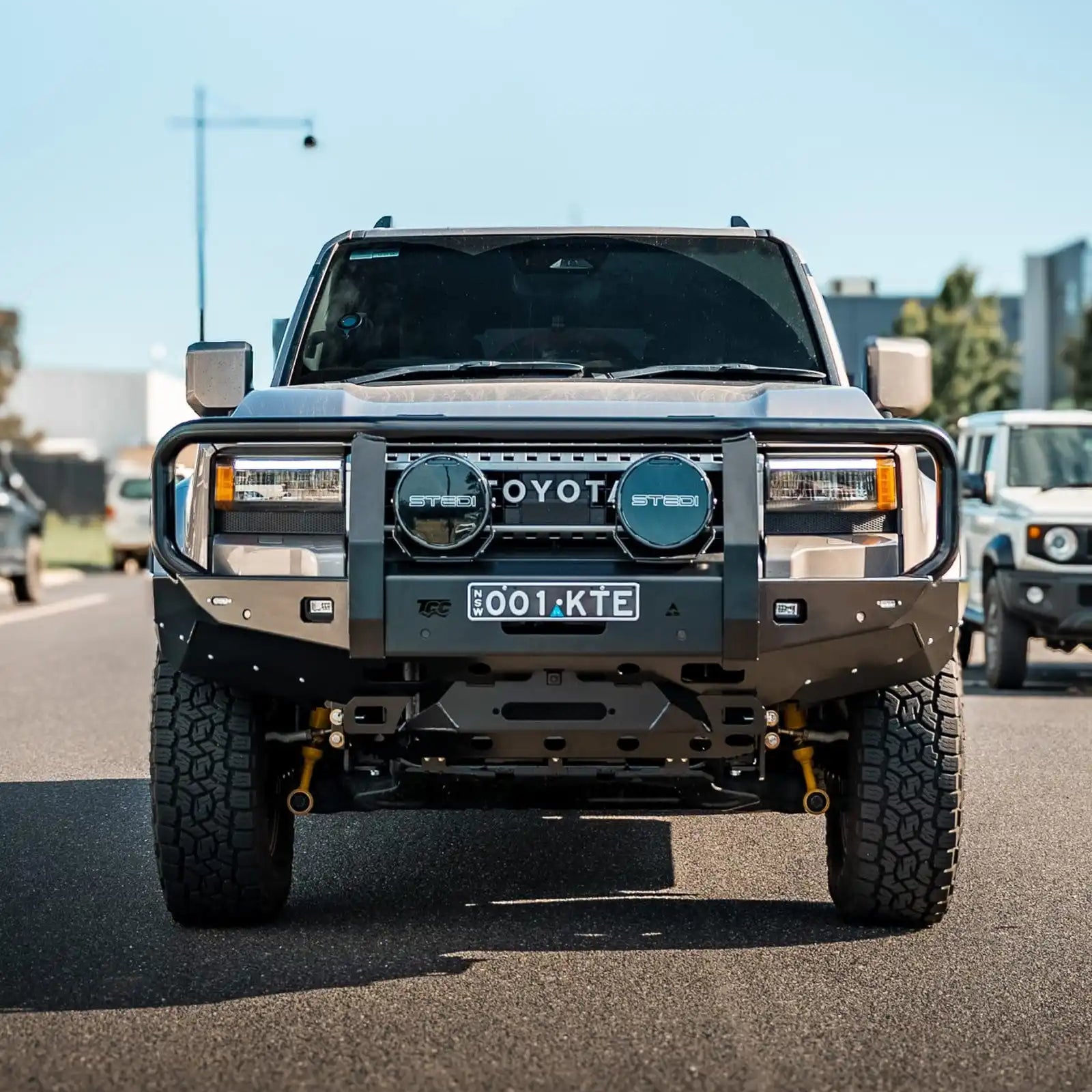 Toyota prado 250 with large front grille and off-road tires on a road.