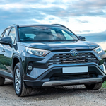 Gray Toyota SUV parked on a dirt road with a grassy field and cloudy sky in the background