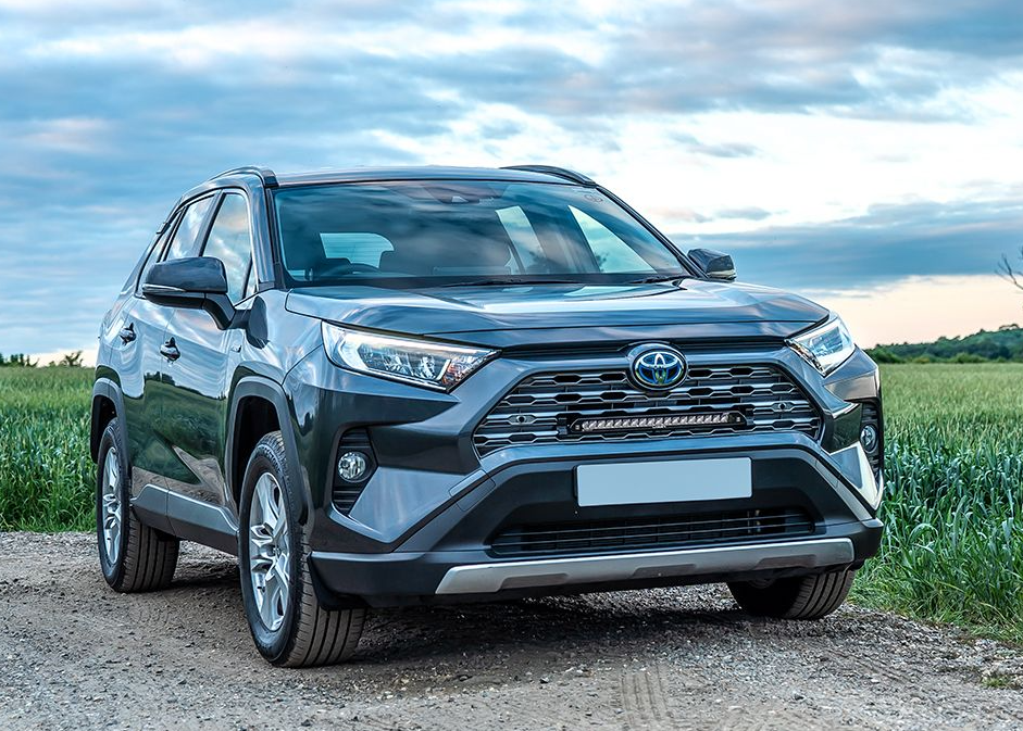 Gray Toyota SUV parked on a dirt road with a grassy field and cloudy sky in the background