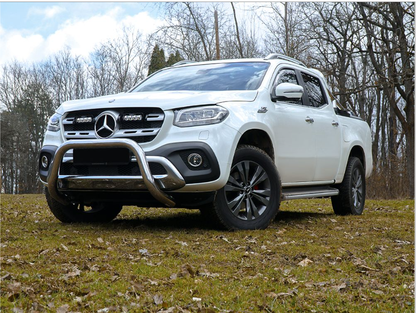 White Mercedes-Benz truck on a grassy field with trees in the background