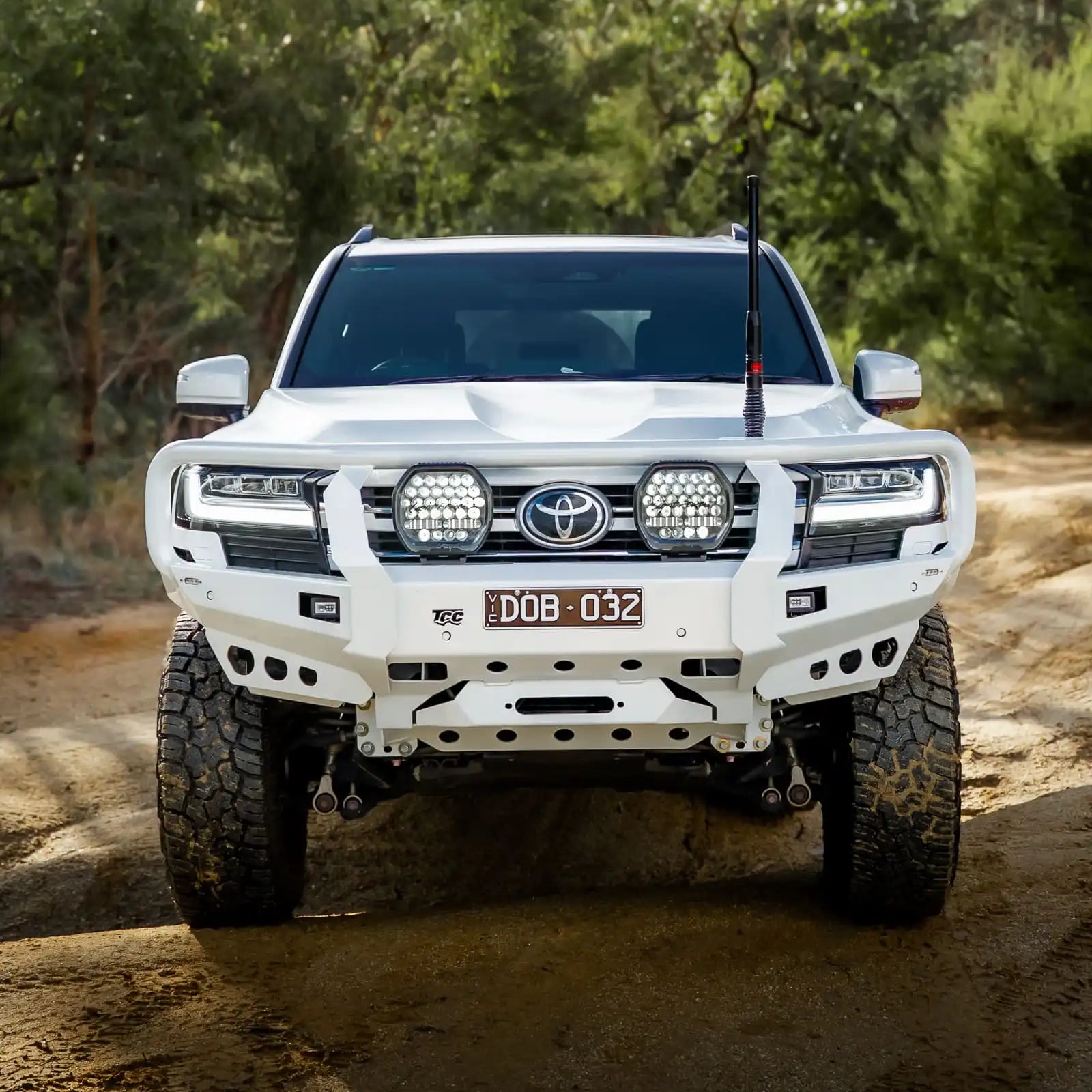 White Toyota SUV on a dirt road with trees in the background