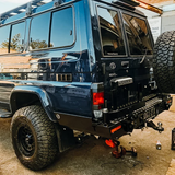 Blue off-road vehicle with large tires and Thorburns LC75/78 Rear Bar on a concrete surface.