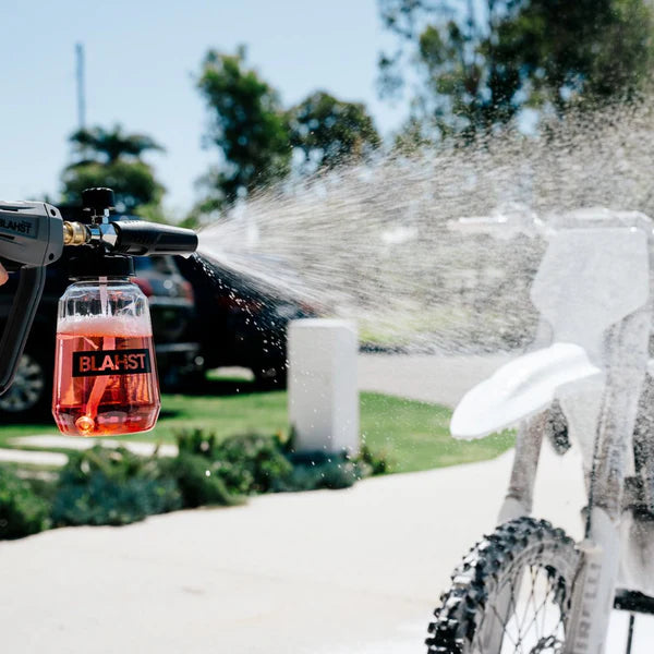 BLAHSHT spray gun cleaning a bike with water outdoors.