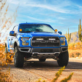 Blue F150 raptor truck on a desert road with cacti and mountains in the background with Lazer Lamps Grille Kit – Ford F-150 Raptor (2017–2020)